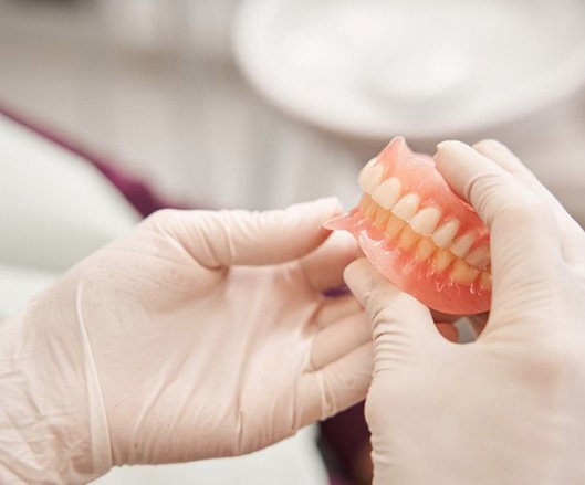 a person with gloves holding a pair of dentures