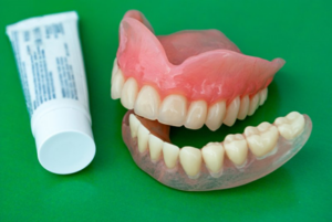 Dentures next to tube of denture adhesive 